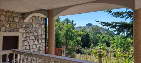 Covered terrace with a stone wall and a view of nature and a hill. - image 4