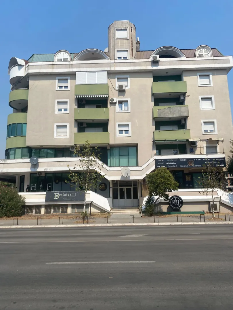 Front facade of a multi-story residential and commercial building with balconies and street access.