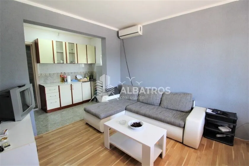 Living room with a sofa set and a view of the kitchen in the background.