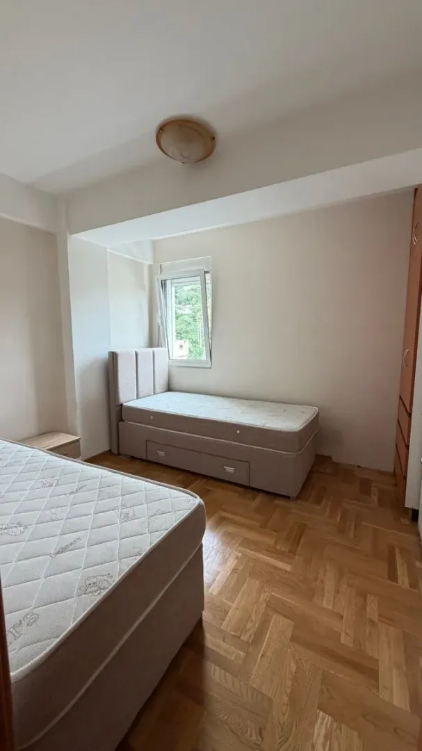 Bedroom with two beds and parquet flooring.