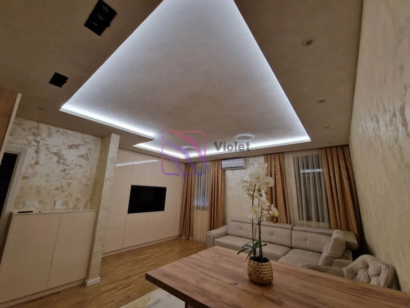 Living room with a sofa set, dining table, and dropped ceiling with LED lighting.
