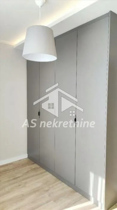 Large grey built-in wardrobe in a bedroom with wooden flooring.
