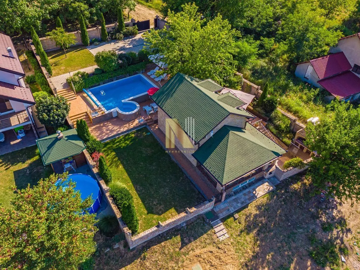 Pogled iz vazduha na kuću sa dvorištem, bazenom i zelenilom.
