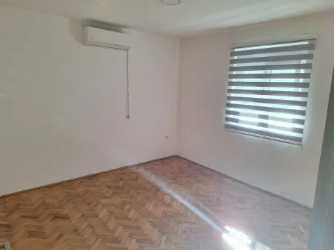 An empty room with parquet flooring, an air conditioner, and zebra blinds on the window. - image 11