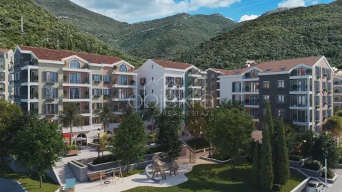 Pogled na kompleks zgrada sa uređenim dvorištem i igralištem u podnožju brda. - image 2