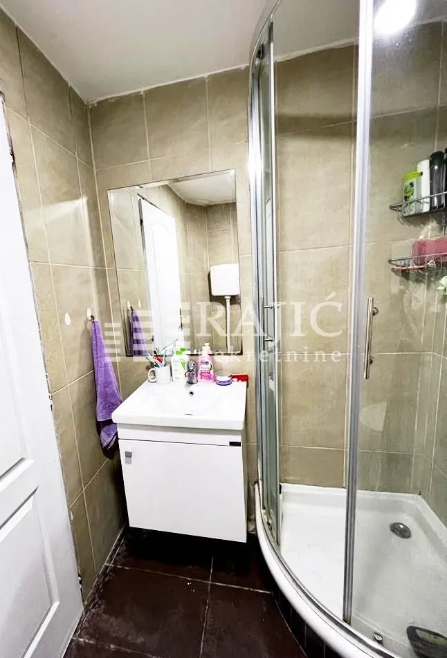Small bathroom with a shower cabin and a sink.