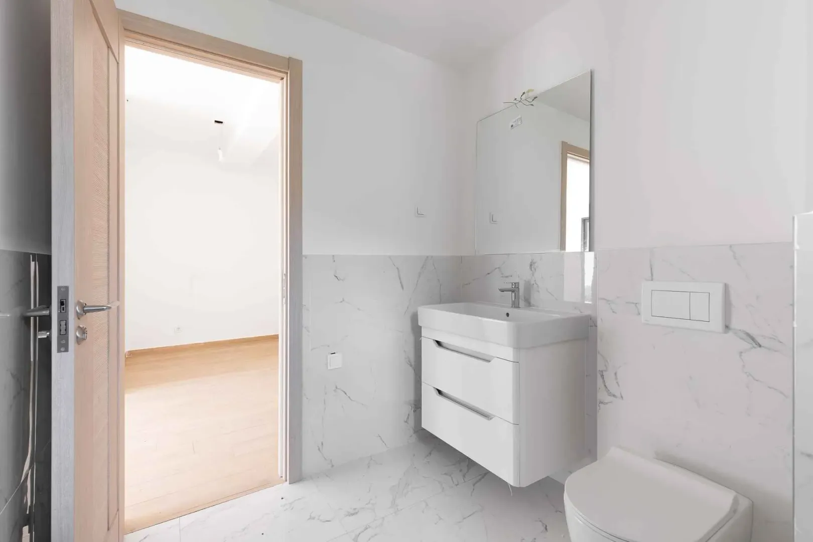 Moderno opremljeno kupatilo sa umivaonikom, ogledalom i WC šoljom.