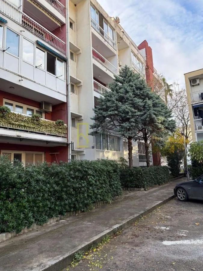 Spoljašnji izgled stambene zgrade sa uređenim dvorištem i zelenilom.