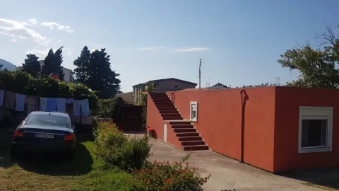 Eksterijer kuće sa dvorištem, spoljnim stepenicama i parkiranim autom. - image 6