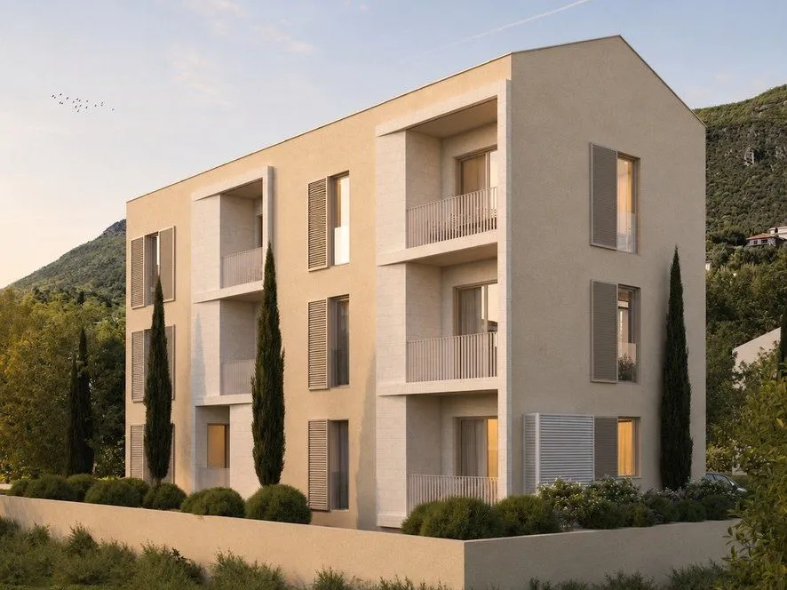 Spoljašnji izgled moderne stambene zgrade sa terasama i uređenim dvorištem.