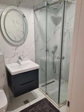 A modern bathroom featuring a glass shower cabin, vanity sink, and a backlit mirror. - image 10