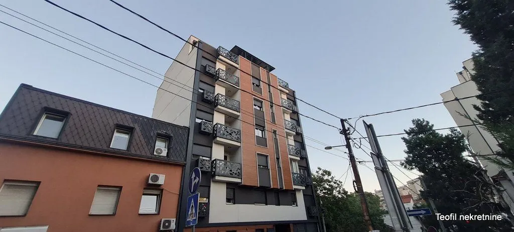 Pogled na spoljašnjost stambene zgrade sa terasam i okolnim ulicama.