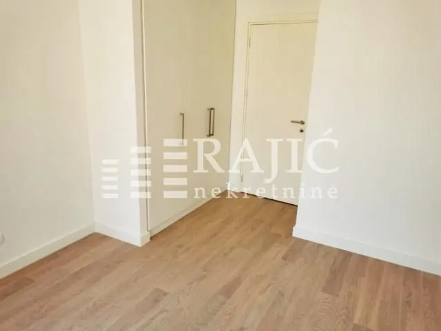 Empty room with a built-in wardrobe and wooden floor.