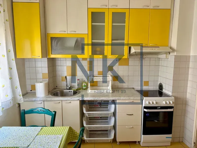 Small kitchen with yellow and white cabinets and a stove.