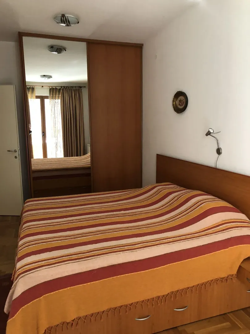 A simple bedroom with a double bed and a mirrored wardrobe.