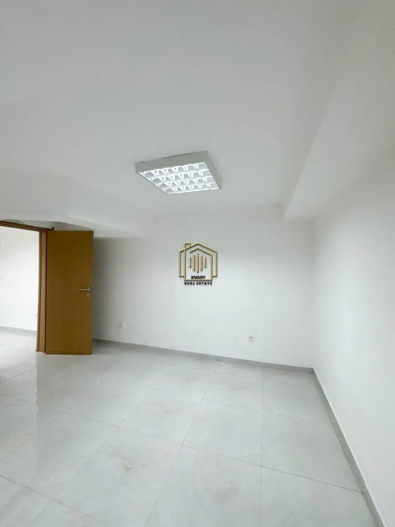 Empty room with white walls, tiled flooring, and an open wooden door.
