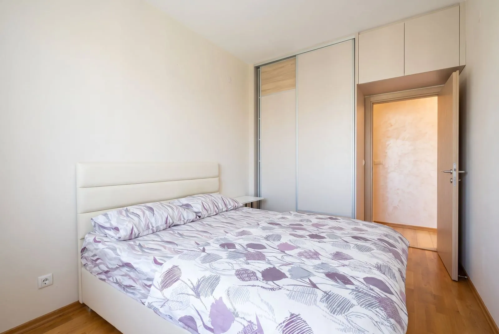 A bedroom featuring a double bed, built-in wardrobe, and laminate flooring.