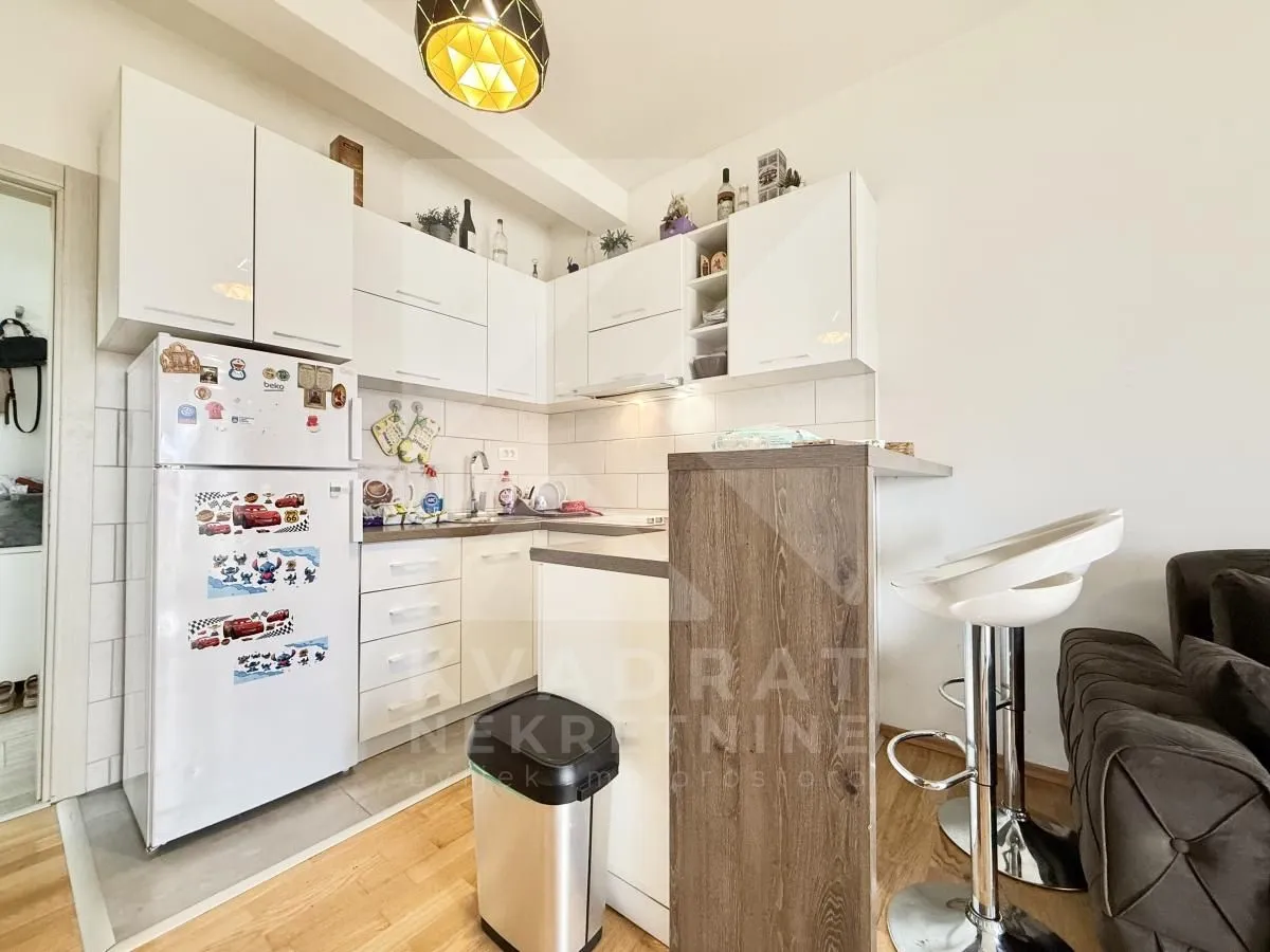 Manja bijela kuhinja sa šankom i barskim stolicama.