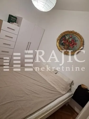 Nameštena spavaća soba sa bračnim krevetom, plakarom i slikom na zidu.