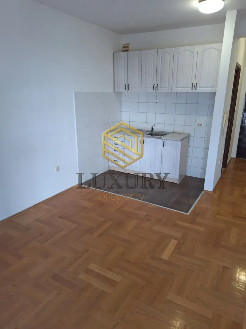 Small kitchen with white cabinets and parquet flooring.
