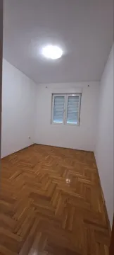 Prazna prostorija sa bijelim zidovima, drvenim parketom i prozorom. - image 7