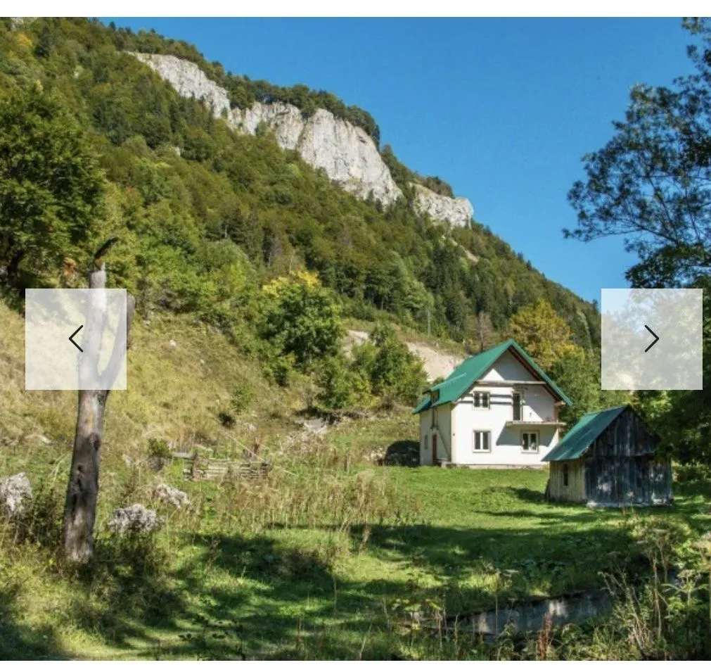 Seoska kuća u planinskom okruženju sa prostranim zelenim dvorištem.