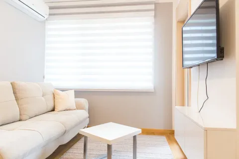 Living room with a sofa, coffee table and wall-mounted TV. - image 6