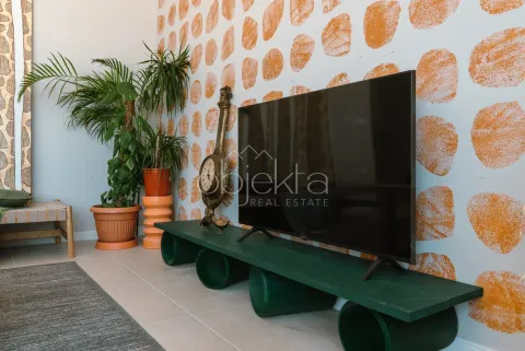 Dnevna soba sa televizorom na zelenoj komodi i ukrasnim biljkama. - image 5