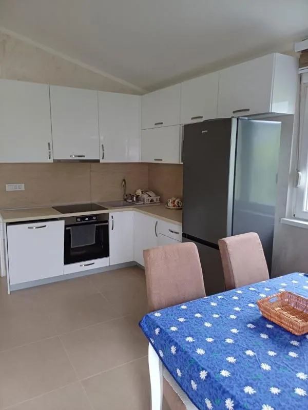 Kitchen equipped with white cabinetry and built-in appliances, featuring a dining table in the foreground.