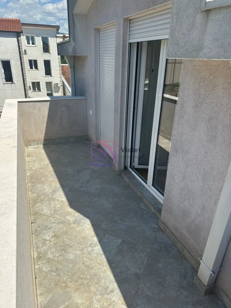 Tiled balcony with room access and window shutters.