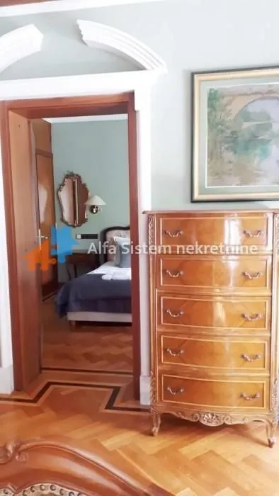 View from the hallway into a bedroom with a wooden dresser in the foreground.