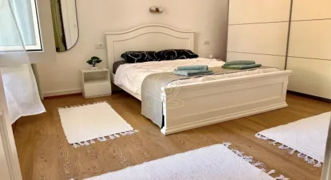 Spavaća soba sa bračnim krevetom, belim nameštajem i drvenim podom. - image 10