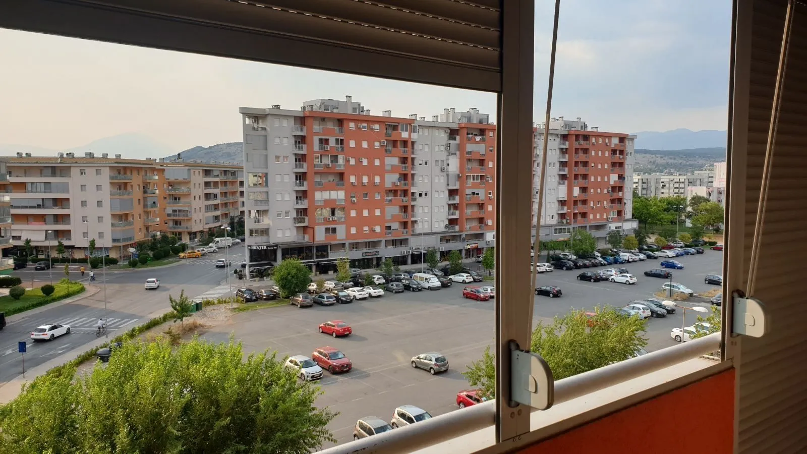 Pogled sa prozora na zgrade i parking.