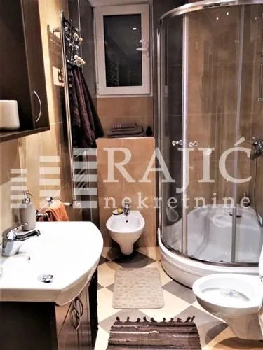 Small bathroom with a shower cabin, washbasin, and toilet fixtures.