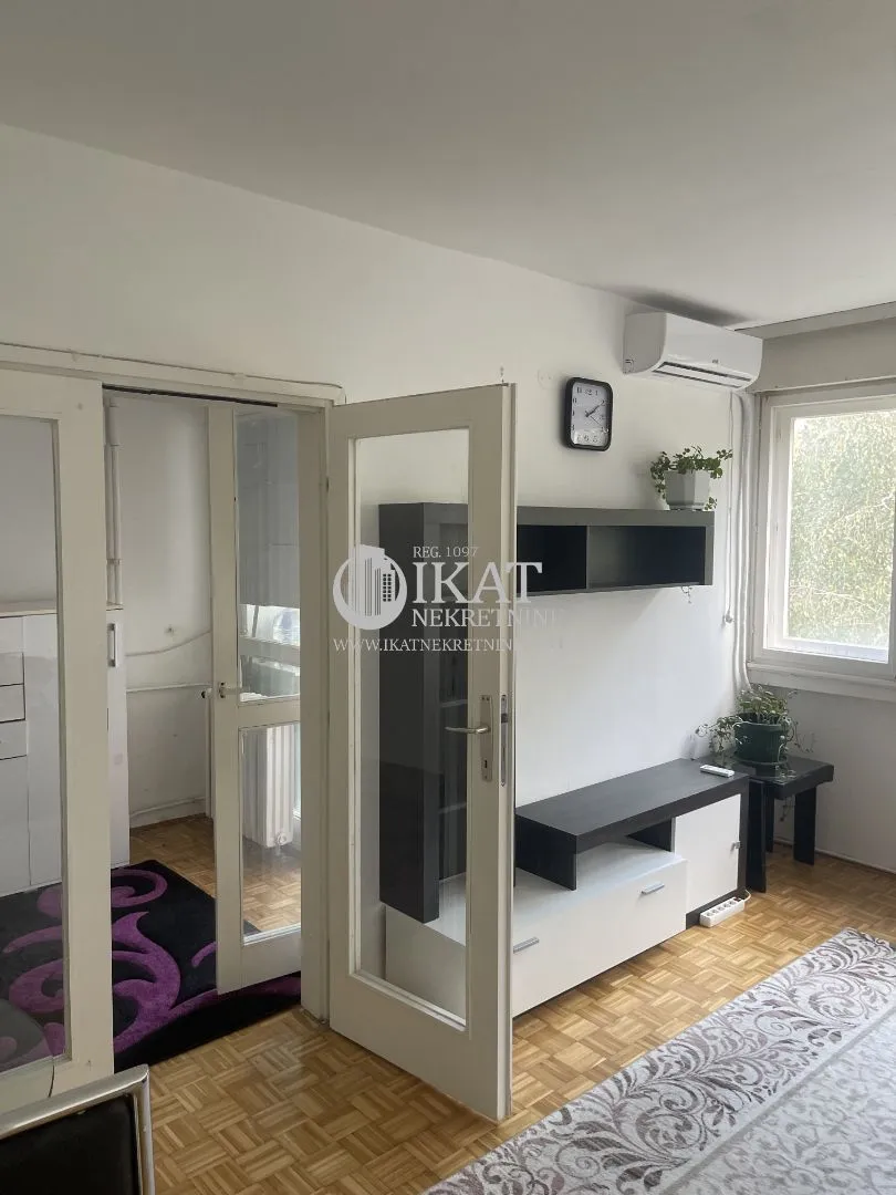 Living room with parquet flooring, furniture, and an air conditioning unit.