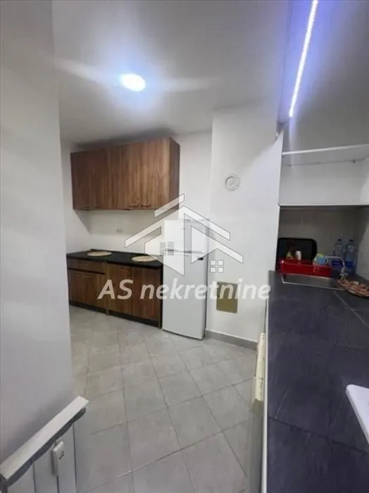 Small kitchen with wooden units and a refrigerator.