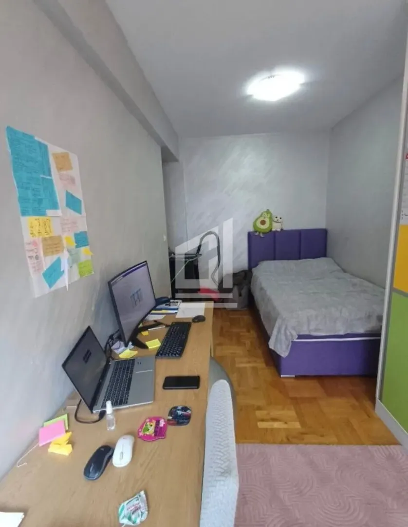 Smaller bedroom with a bed and a desk with a computer.