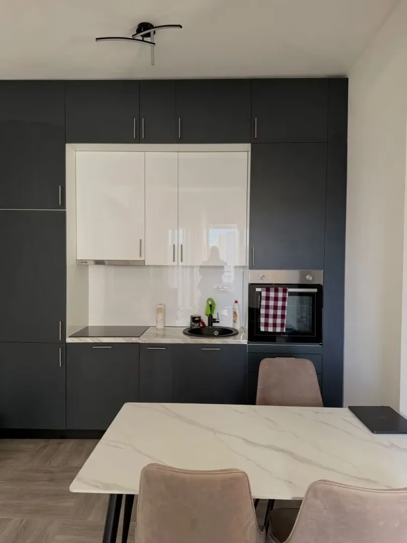 Modern kitchen with dark cabinetry and a dining table.