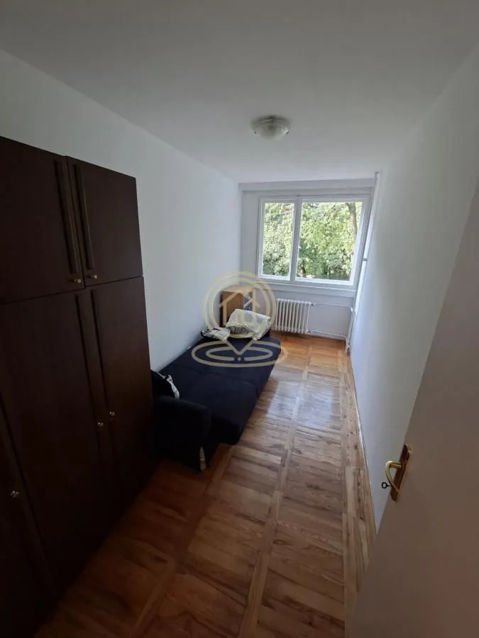 Manja spavaća soba sa krevetom na razvlačenje i velikim drvenim ormarom.