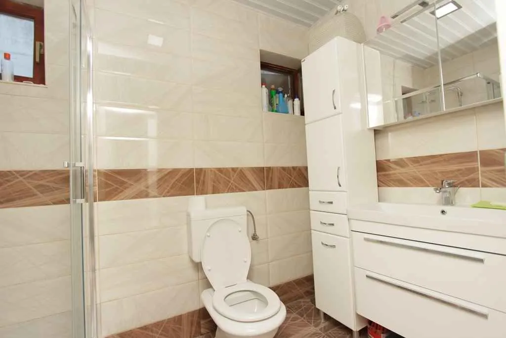 Svijetlo kupatilo sa bijelim elementima i tuš kabinom.