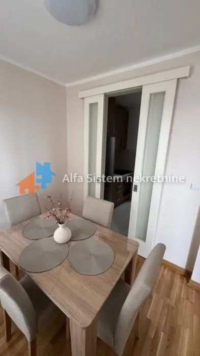 Trpezarija sa stolom i stolicama i kliznim vratima koja vode u kuhinju.