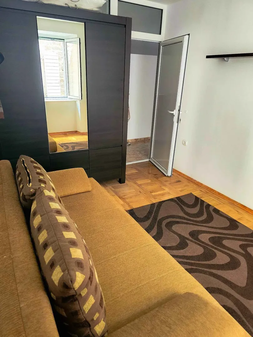 Living room with a sofa, large wardrobe and wooden flooring.