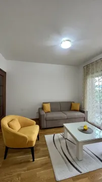 Dnevna soba sa sivim kaučem, žutom foteljom i bijelim klub stolom. - image 2