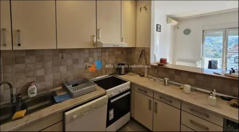 Smaller kitchen with wood-patterned cabinets and a breakfast bar overlooking the living room. - image 22