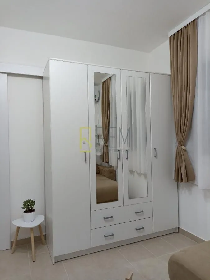 Svijetla spavaća soba sa velikim bijelim garderoberom sa ogledalima.