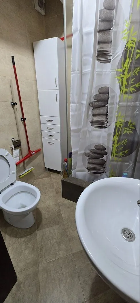 Small bathroom with a sink, toilet, white cabinet, and shower cabin.