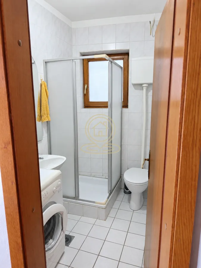 Manje kupatilo sa tuš kabinom, umivaonikom, wc šoljom i veš mašinom.