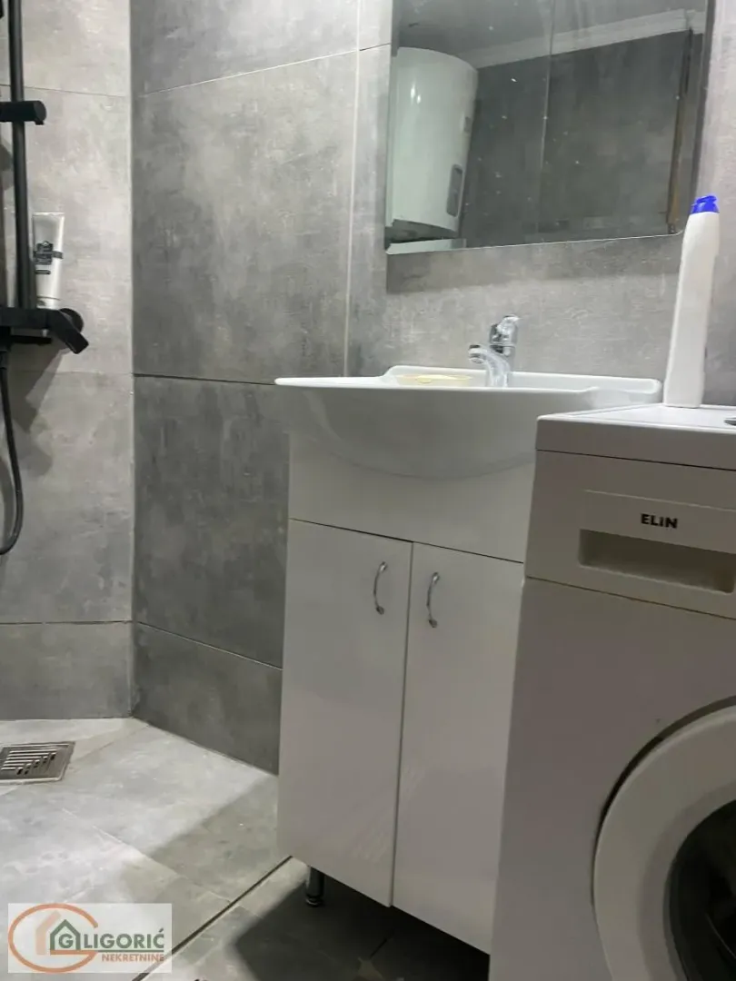 Bathroom with a shower cabin, washbasin, and washing machine.
