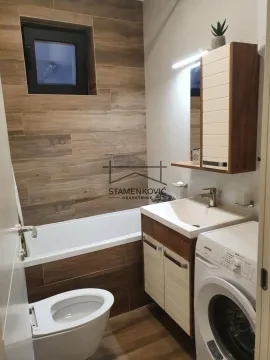 Small bathroom with a bathtub, washbasin, toilet bowl, and washing machine. - image 5