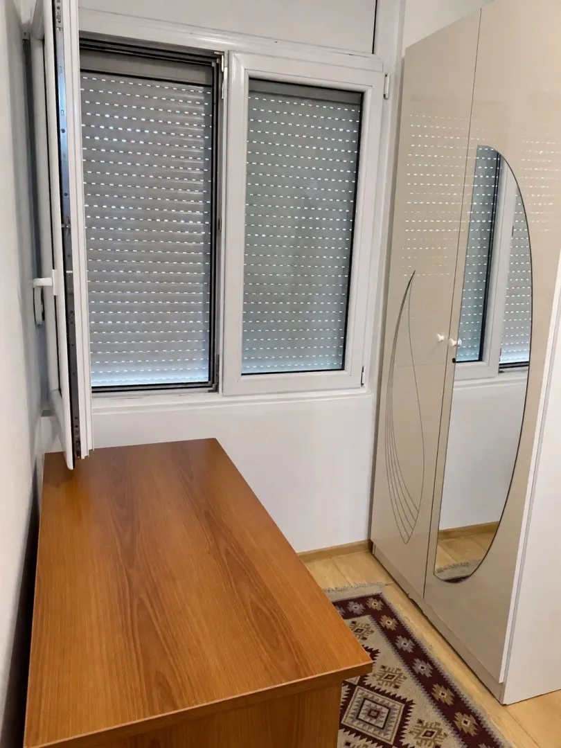 Small room with a desk, wardrobe, and window with blinds.